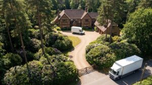 Long gravel driveway with a small van at the house and a larger lorry at the gate